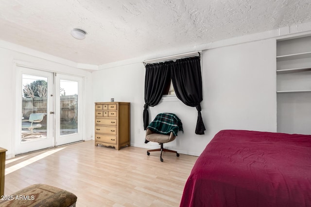 bedroom featuring access to outside, wood finished floors, french doors, and a textured ceiling