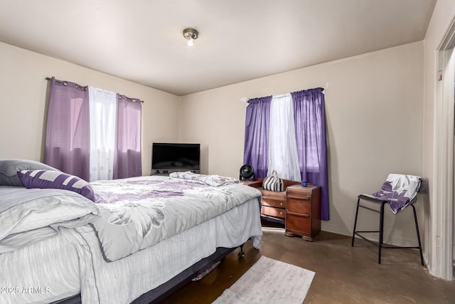 bedroom with baseboards and finished concrete floors