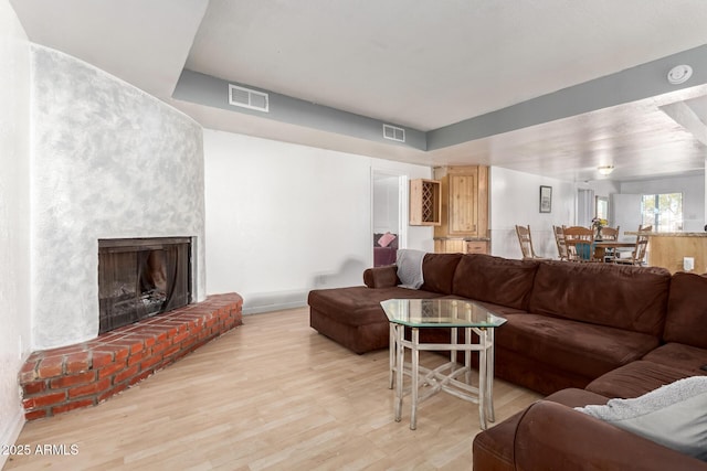 living area with visible vents, a fireplace, baseboards, and light wood-style floors