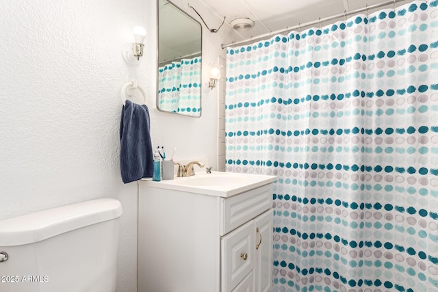 full bath with toilet, vanity, a shower with shower curtain, and a textured wall