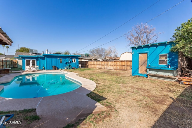 view of swimming pool featuring an outbuilding, a lawn, a fenced backyard, and a fenced in pool