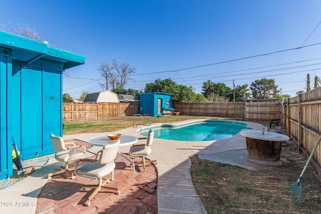 view of swimming pool with a patio, a fenced in pool, a shed, a fenced backyard, and an outdoor structure