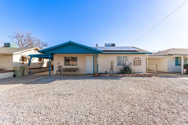 ranch-style house featuring covered porch and solar panels