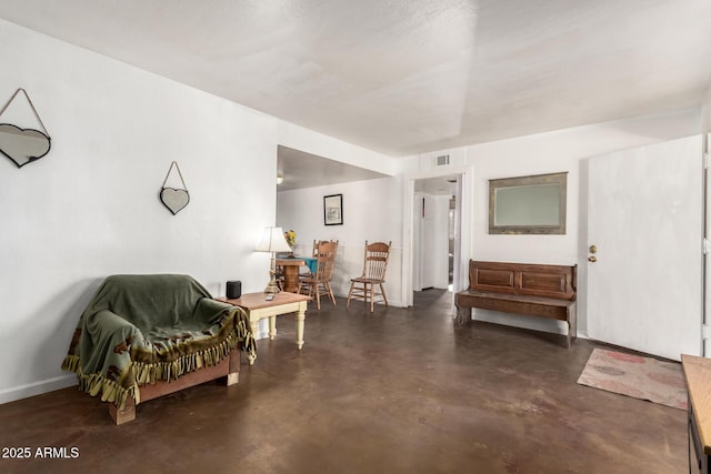 living area featuring visible vents, baseboards, and concrete floors