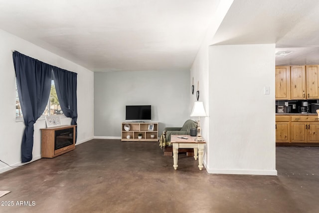 living area featuring concrete floors and baseboards