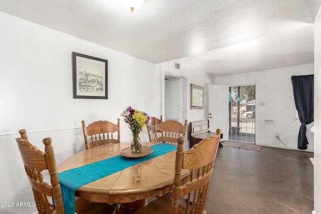 dining space featuring a textured ceiling, visible vents, and finished concrete floors