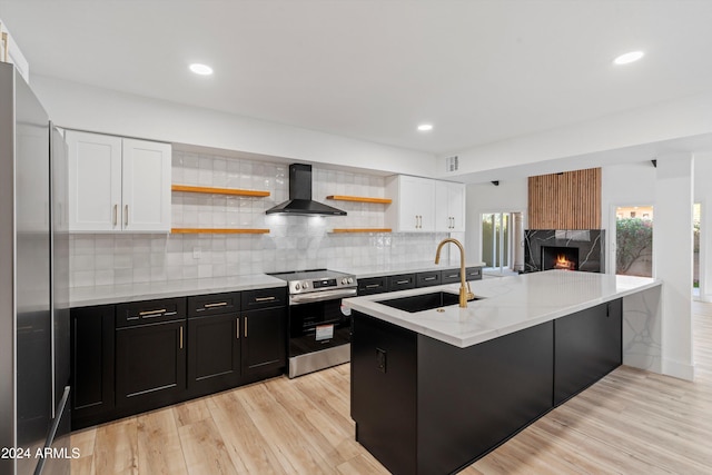 kitchen featuring stainless steel electric range, light hardwood / wood-style floors, white cabinets, sink, and wall chimney range hood