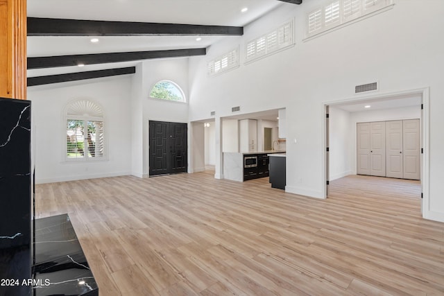 unfurnished living room with light wood-type flooring, beamed ceiling, and high vaulted ceiling