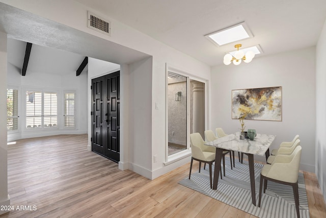 dining space with an inviting chandelier, vaulted ceiling with beams, and light hardwood / wood-style flooring