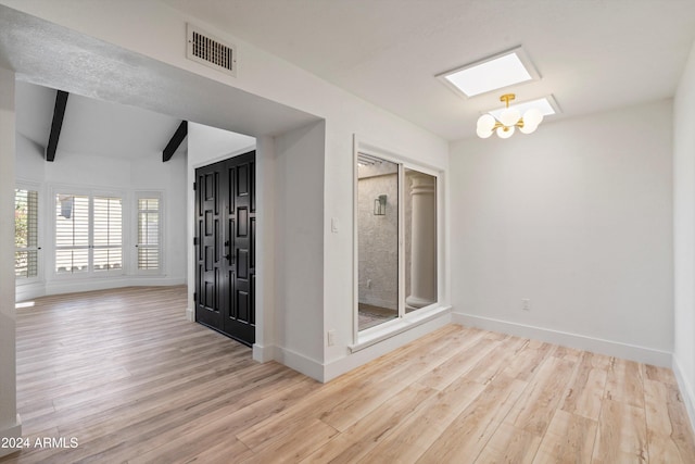 spare room with lofted ceiling with beams, light hardwood / wood-style flooring, and an inviting chandelier