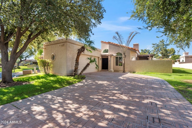 mediterranean / spanish home with a garage and a front lawn