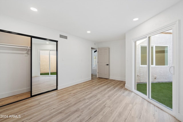 unfurnished bedroom with access to exterior, a closet, and light wood-type flooring