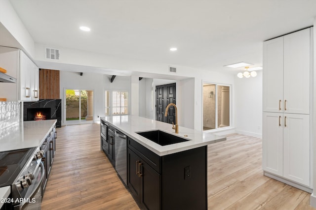 kitchen featuring white cabinetry, appliances with stainless steel finishes, sink, and a center island with sink