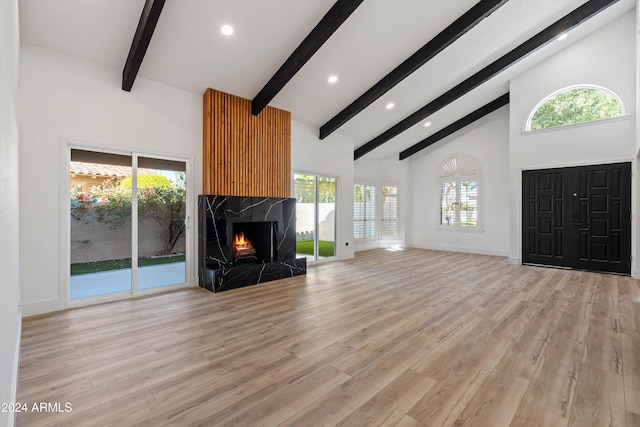 unfurnished living room featuring high vaulted ceiling, light hardwood / wood-style flooring, beamed ceiling, and a fireplace