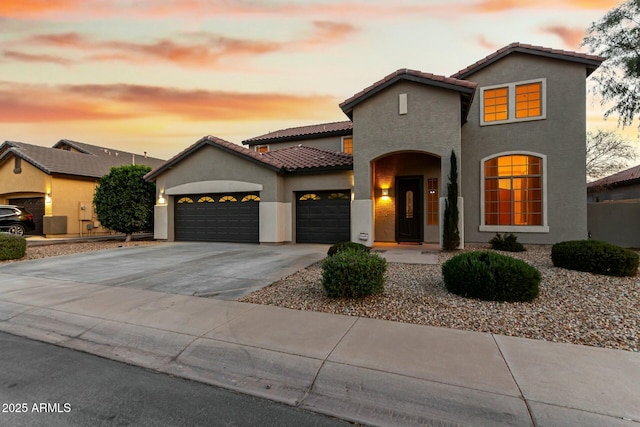 view of front of property featuring a garage, driveway, a tiled roof, and stucco siding