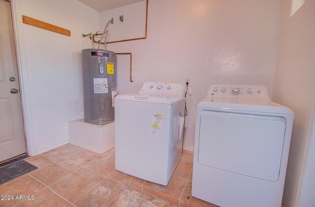 washroom featuring electric water heater, light tile patterned floors, and washer and clothes dryer