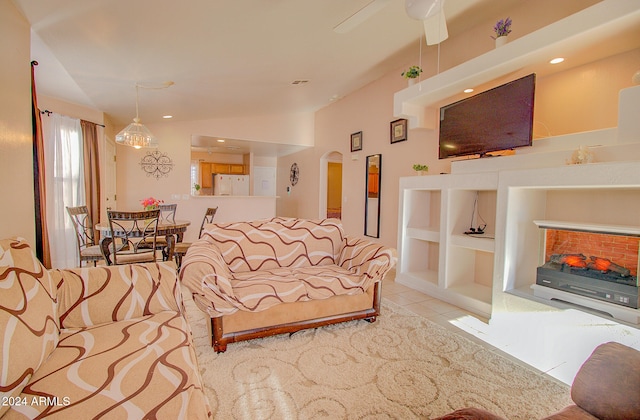 tiled living room featuring lofted ceiling, ceiling fan, and a fireplace