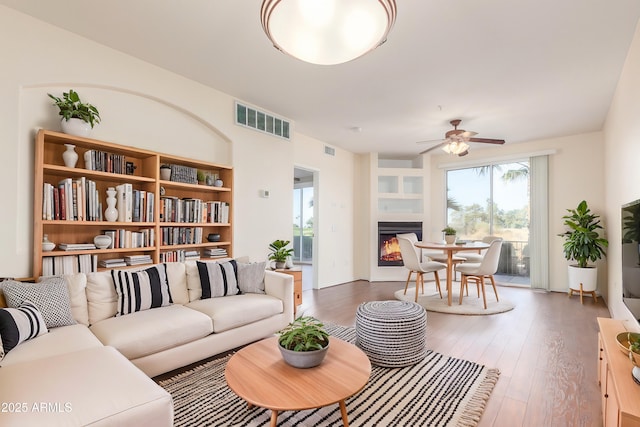 living room featuring dark wood-type flooring and ceiling fan