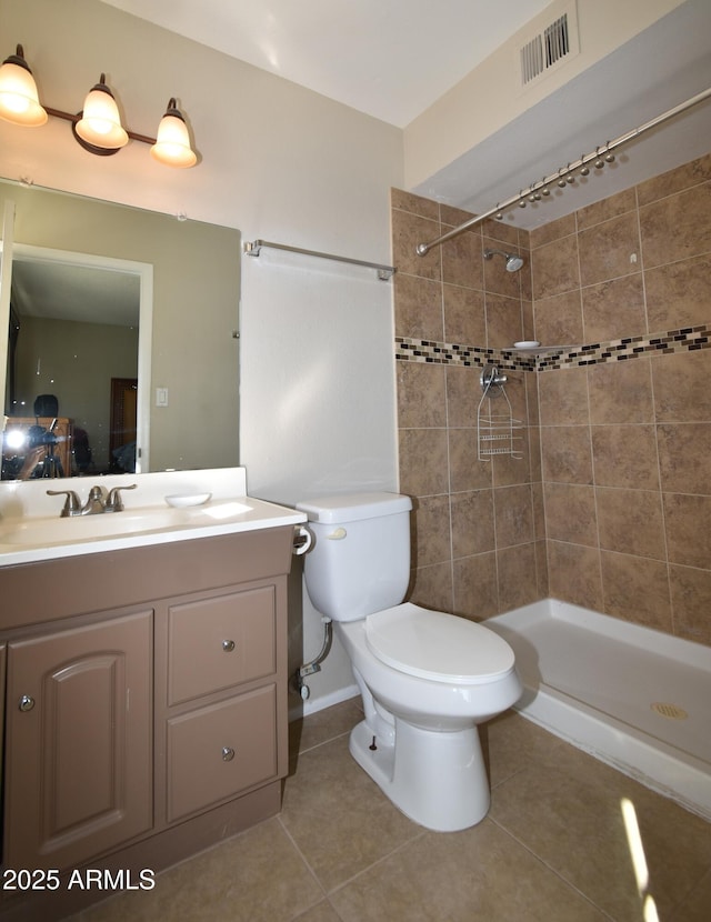 bathroom featuring vanity, tiled shower, toilet, and tile patterned floors