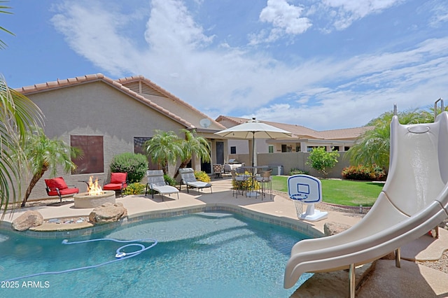 view of pool with a fire pit, a water slide, a patio, and fence