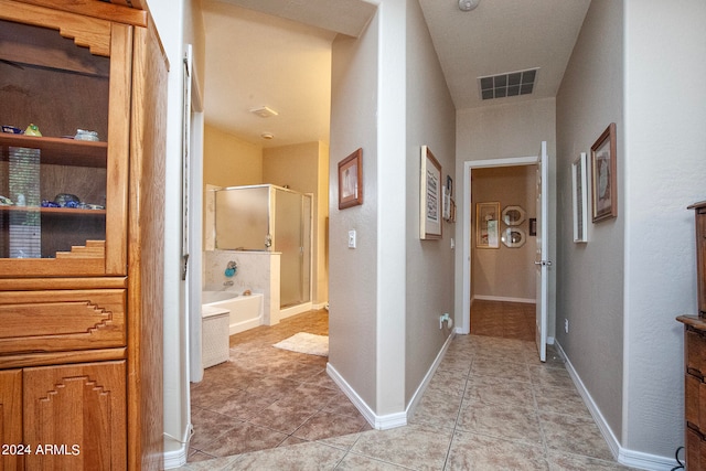 corridor featuring a textured ceiling and light tile patterned flooring