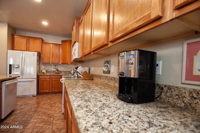 kitchen with light stone countertops, white appliances, and dark tile patterned floors