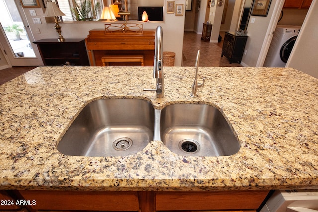 details featuring sink, light stone counters, and washer / dryer