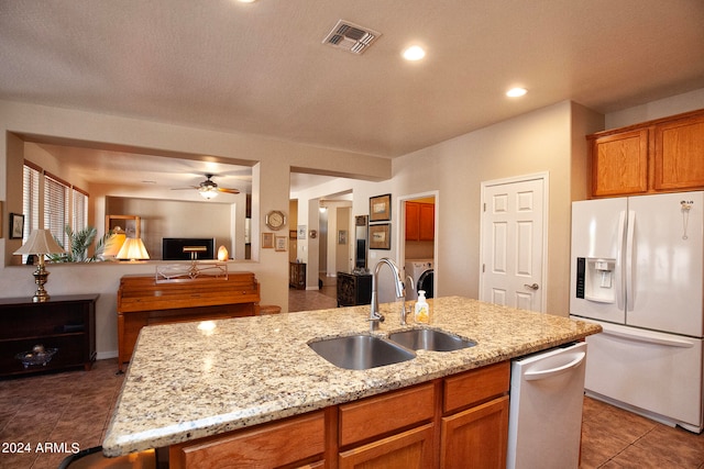 kitchen with ceiling fan, stainless steel dishwasher, white refrigerator with ice dispenser, washer / dryer, and sink