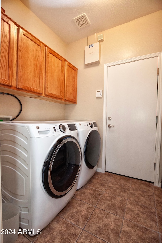 clothes washing area with independent washer and dryer, cabinets, and dark tile patterned floors