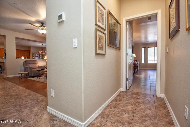 hallway with tile patterned flooring and an inviting chandelier