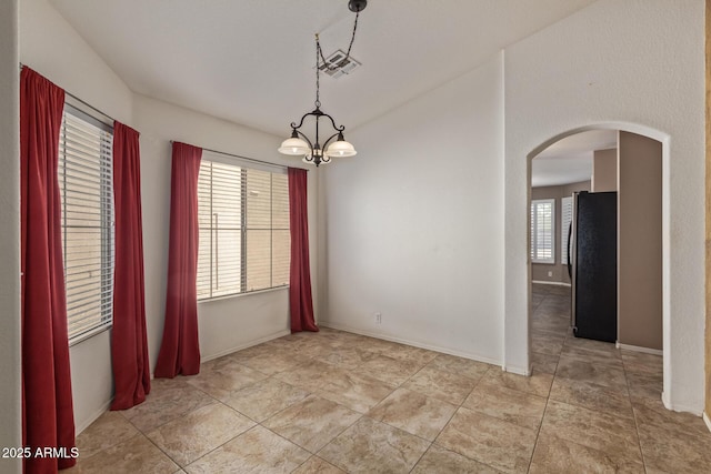 spare room featuring baseboards, arched walkways, light tile patterned floors, and a notable chandelier