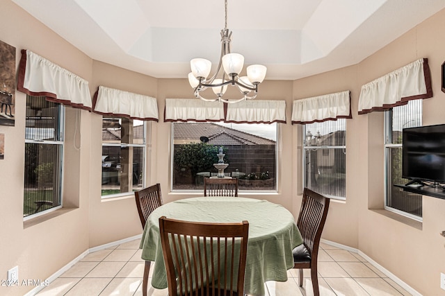 dining area with a notable chandelier, light tile patterned flooring, and a tray ceiling