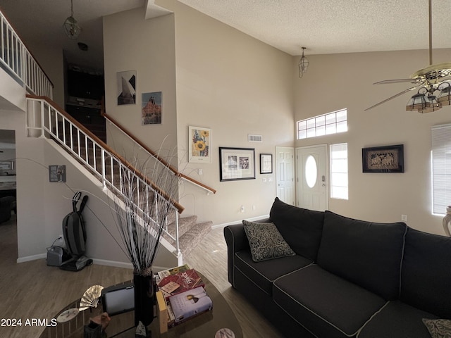 living room with ceiling fan, high vaulted ceiling, a textured ceiling, and hardwood / wood-style flooring