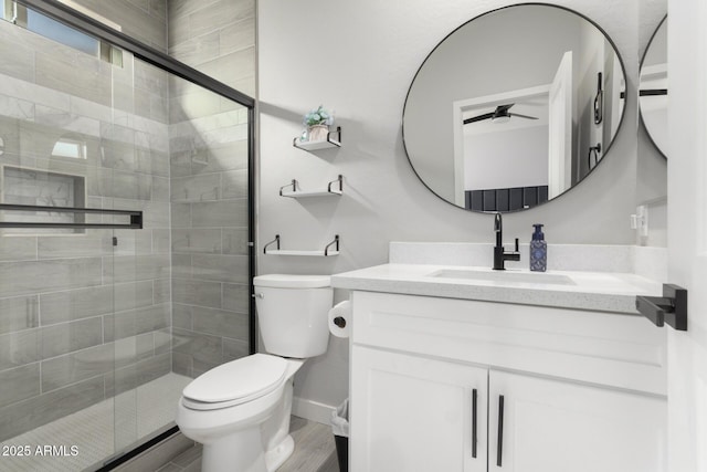 bathroom featuring ceiling fan, wood-type flooring, an enclosed shower, toilet, and vanity