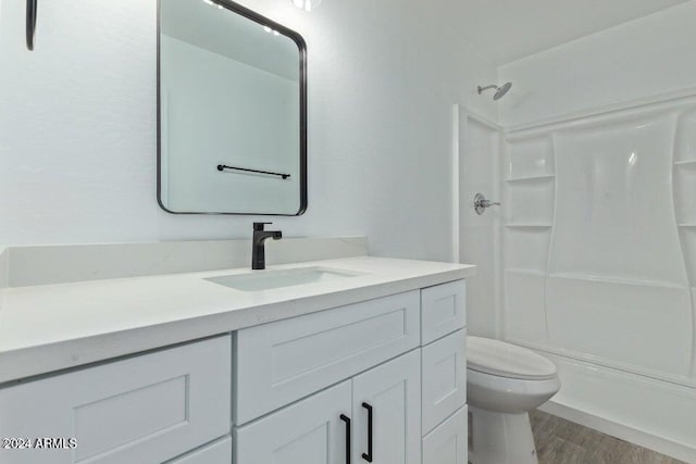 bathroom with vanity, hardwood / wood-style floors, toilet, and a shower