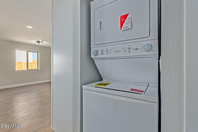 clothes washing area with stacked washer and dryer and light wood-type flooring