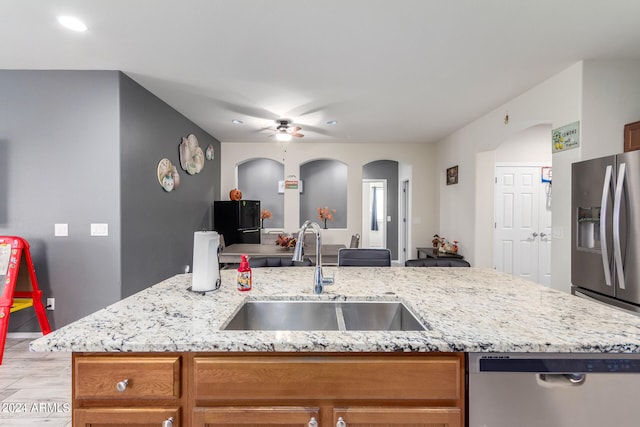 kitchen featuring ceiling fan, an island with sink, sink, stainless steel appliances, and light hardwood / wood-style floors