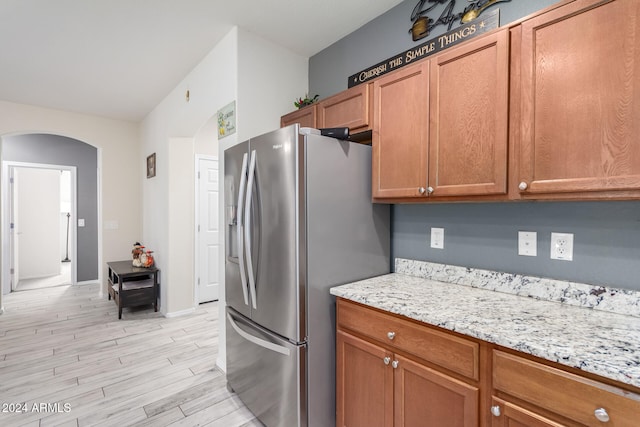 kitchen with light stone countertops, stainless steel fridge with ice dispenser, and light wood-type flooring