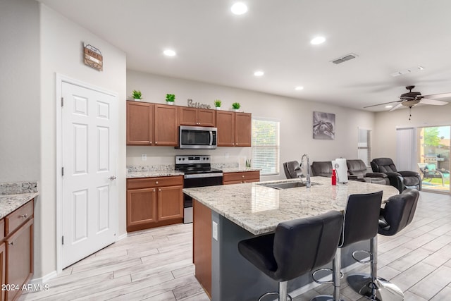 kitchen with an island with sink, appliances with stainless steel finishes, sink, and a breakfast bar