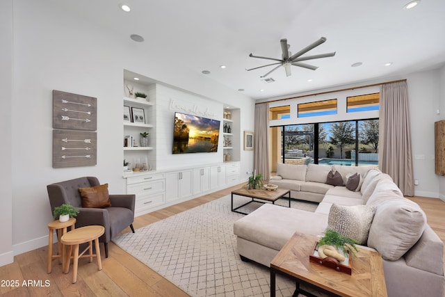 living room with built in shelves and light hardwood / wood-style floors