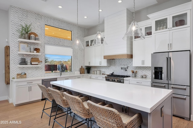 kitchen featuring a breakfast bar, a center island, pendant lighting, stainless steel appliances, and white cabinets