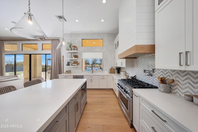 kitchen featuring premium range hood, pendant lighting, white cabinetry, decorative backsplash, and high end stainless steel range