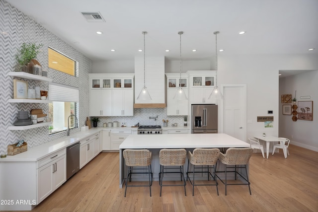 kitchen with premium range hood, sink, white cabinetry, a center island, and stainless steel appliances