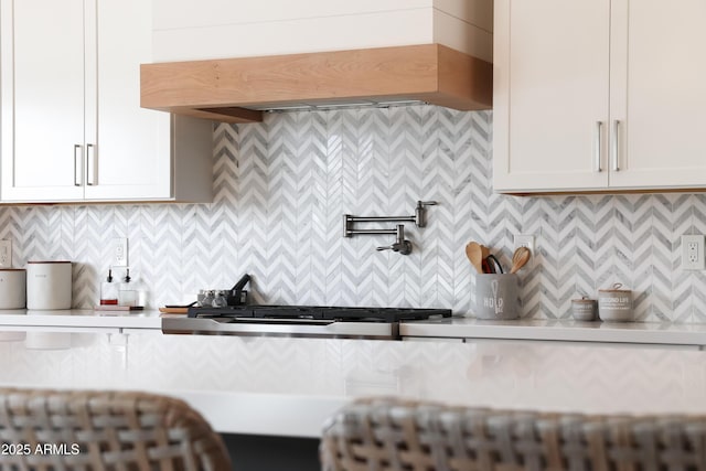 kitchen featuring premium range hood, tasteful backsplash, and white cabinets