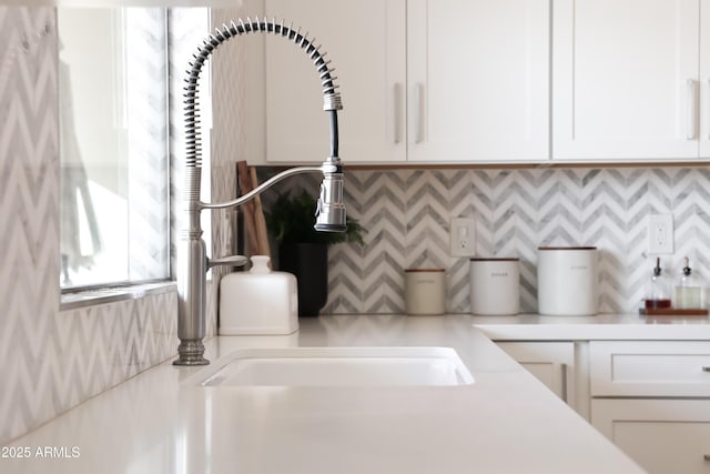 room details with sink, decorative backsplash, and white cabinets