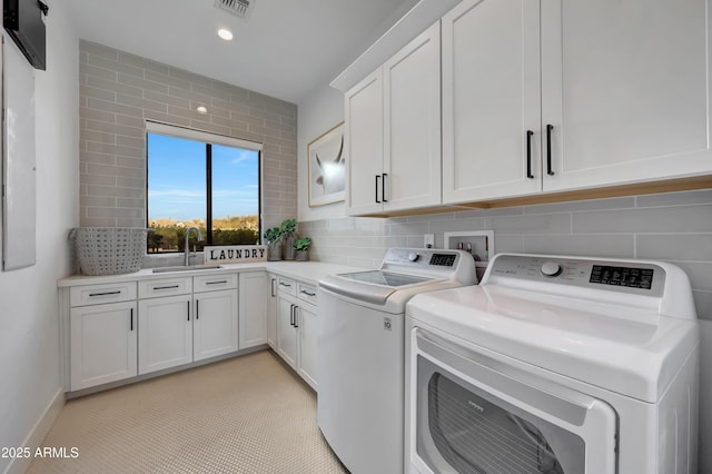 laundry room featuring cabinets, sink, and washer and clothes dryer