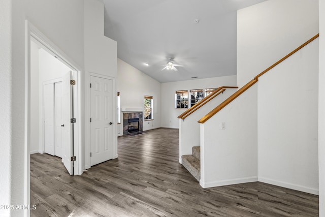 foyer with wood finished floors, baseboards, ceiling fan, stairs, and a tile fireplace