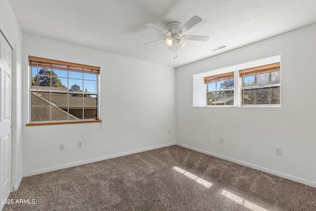 empty room featuring a wealth of natural light, visible vents, baseboards, and carpet flooring