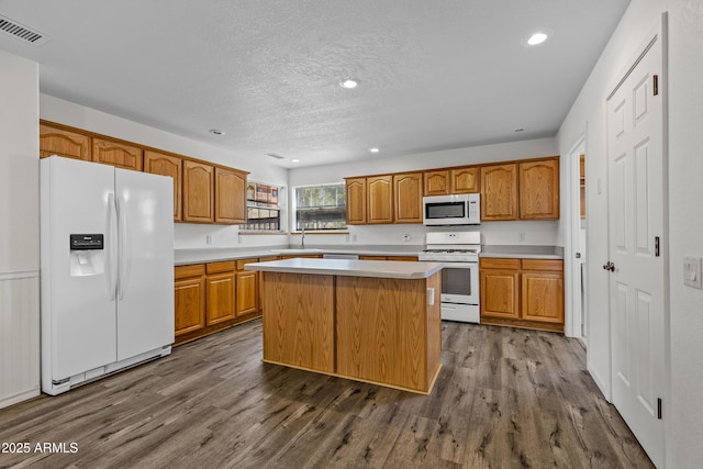 kitchen featuring white appliances, dark wood-style floors, visible vents, and light countertops