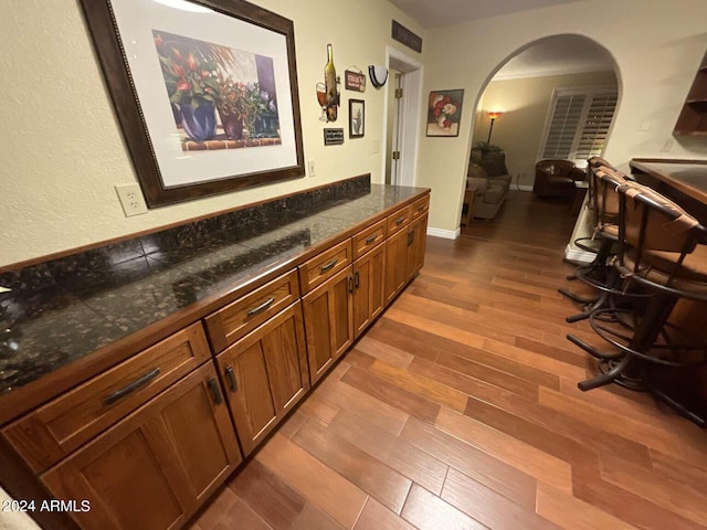 interior space featuring arched walkways, dark wood-style flooring, visible vents, and baseboards